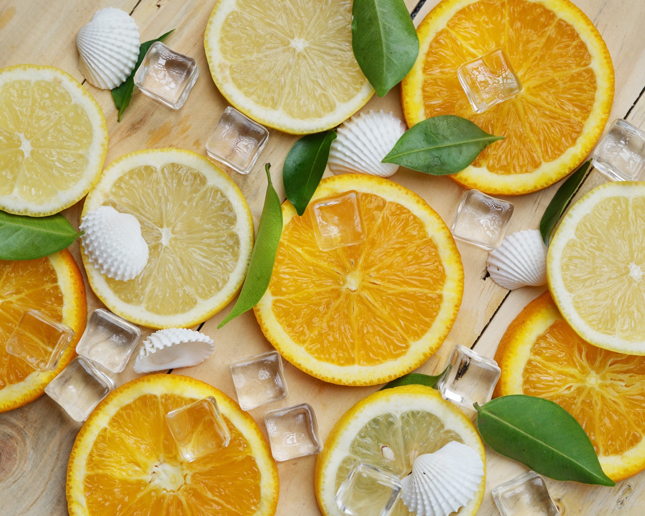 Кусочки апельсина и лимона на столе с кубиками льда и ракушками