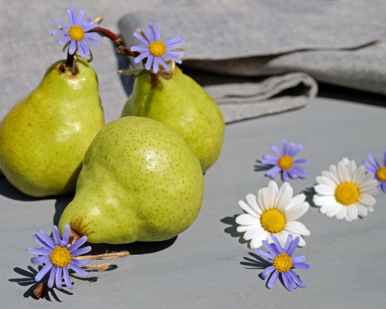 Три груши на столе с цветами