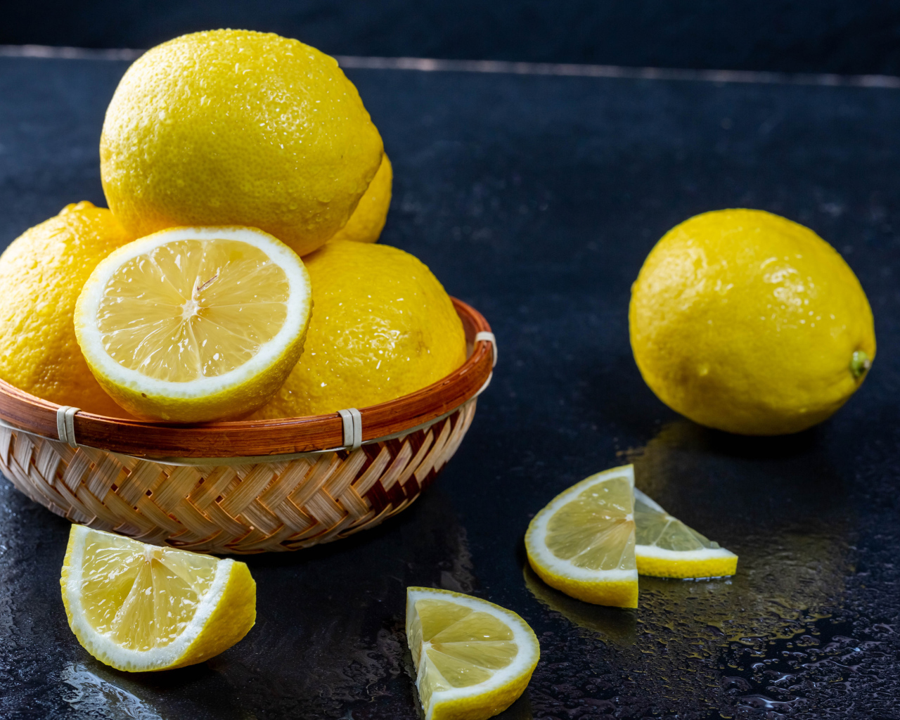 Мокрый лимон с кусочками на черном столе 