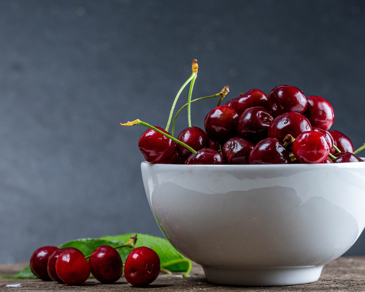 Белая фарфоровая тарелка с красной спелой черешней 