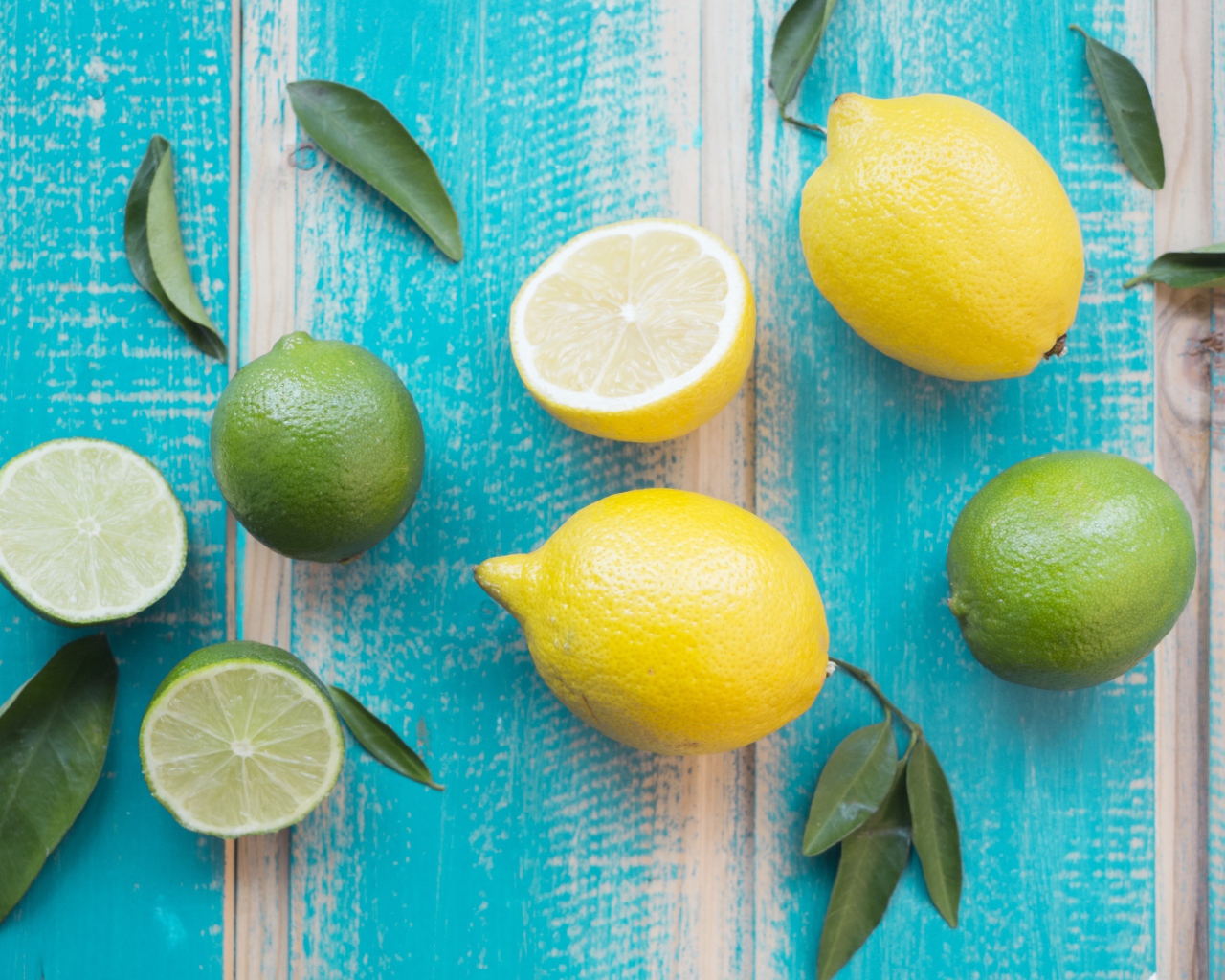 Желтые лимоны и зеленые плоды лайма на столе 