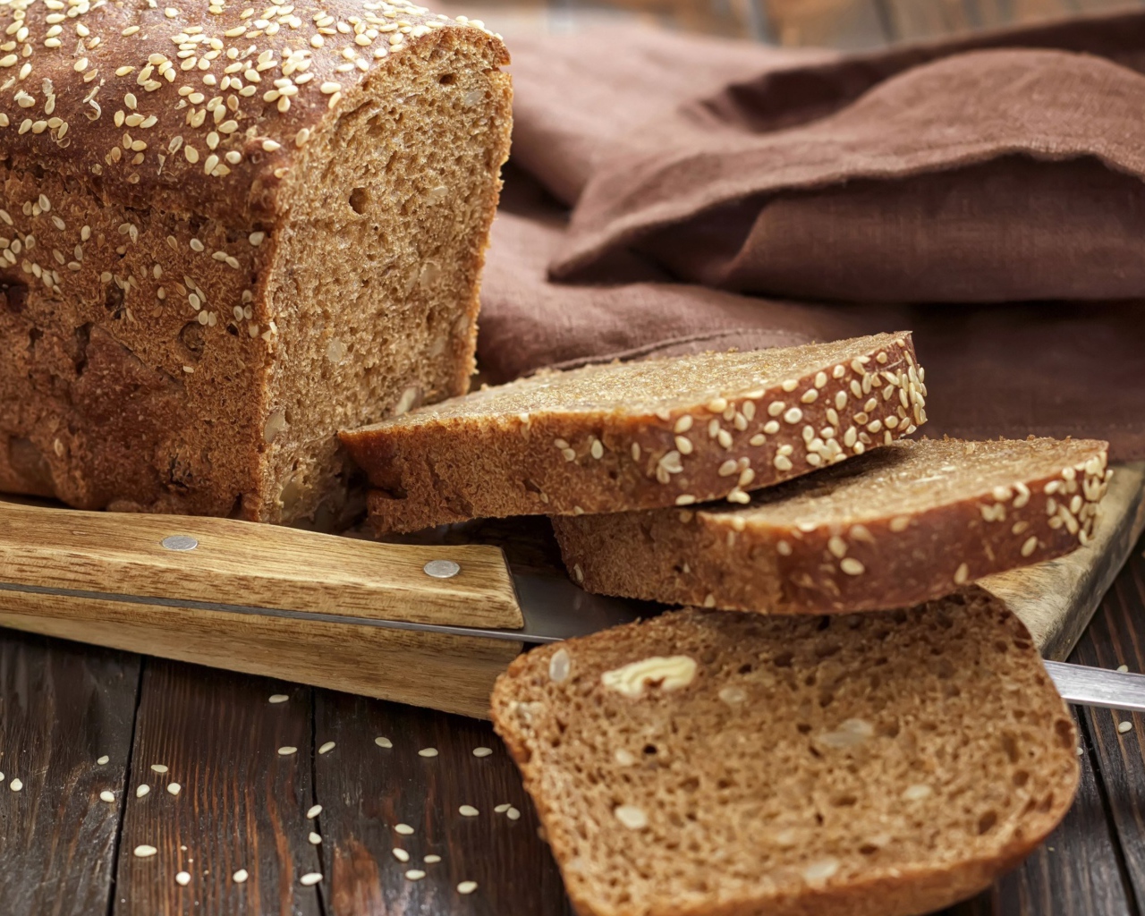 Буханка хлеба нарезанная кусочками на столе с ножом