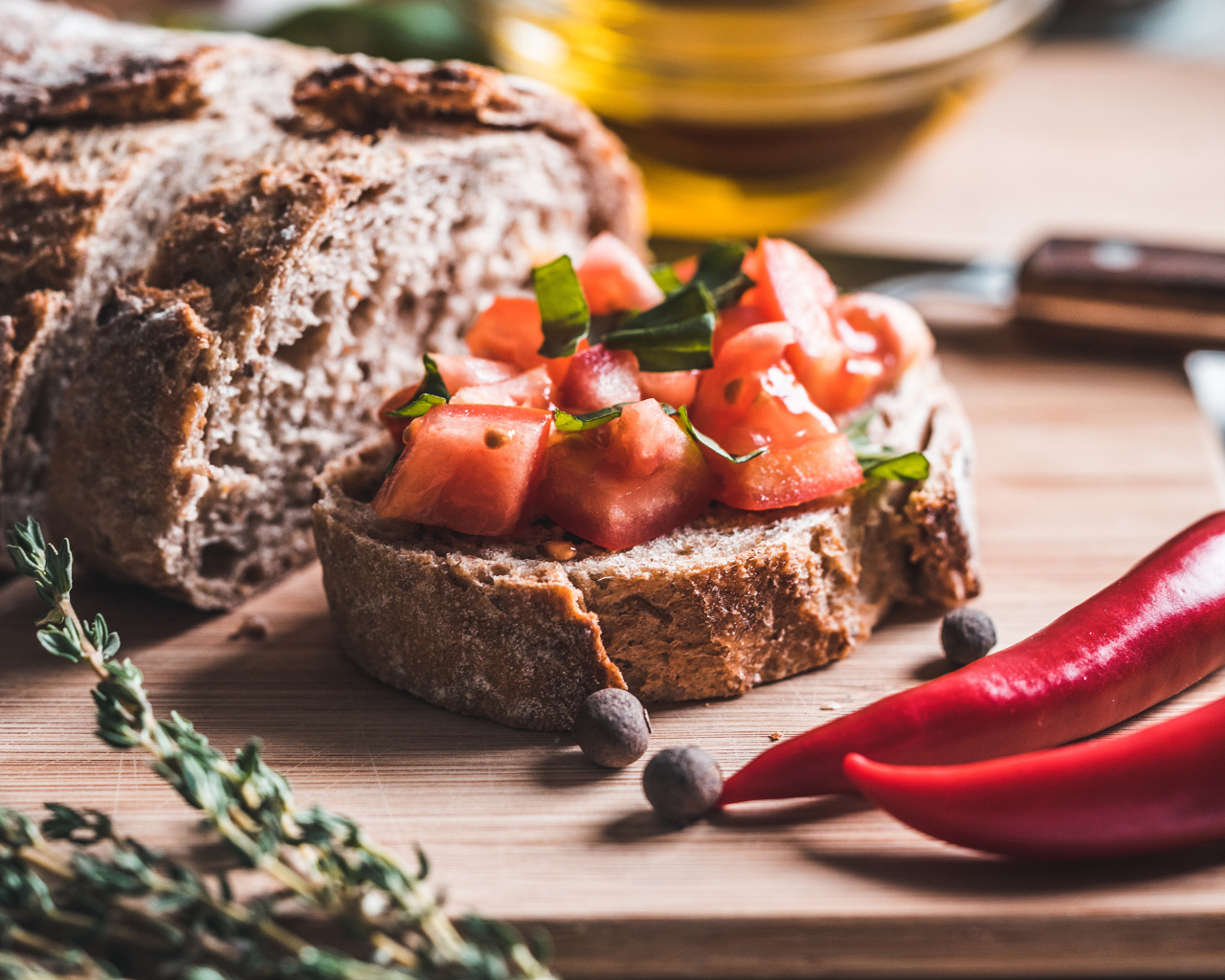 Черный хлеб с кусочками помидора на столе с острым красным перцем