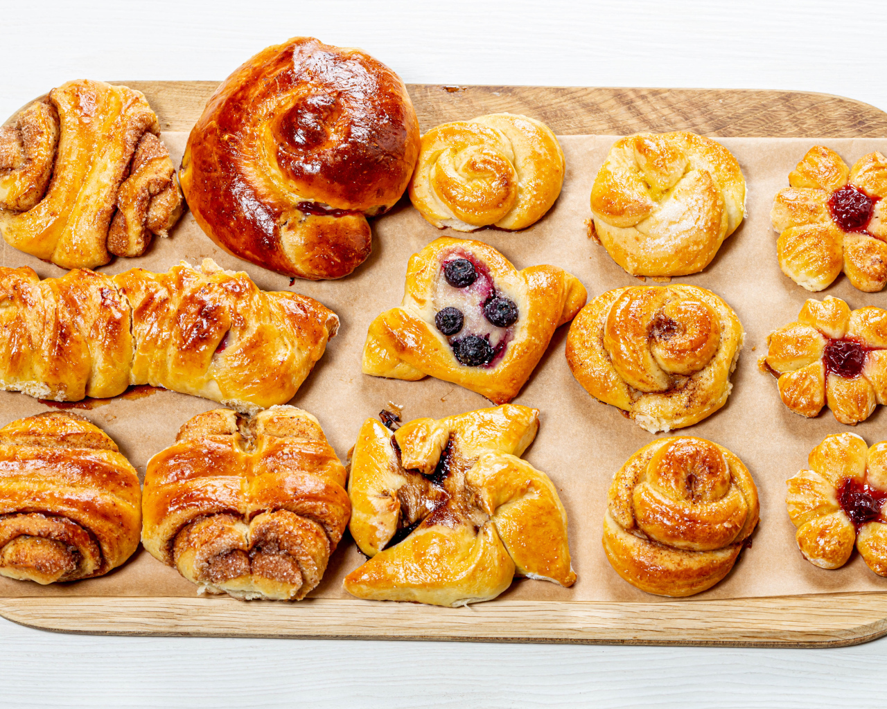 Разная свежая выпечка на доске на белом фоне