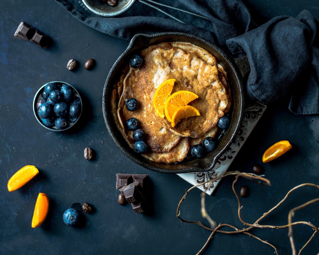 Блины с ягодами черники и апельсинами на столе 