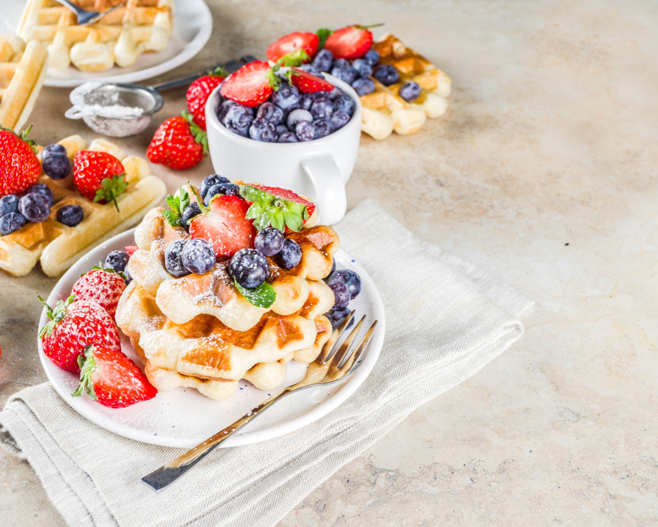 Вкусные сладкие вафли на тарелке с ягодами и сахарной пудрой 