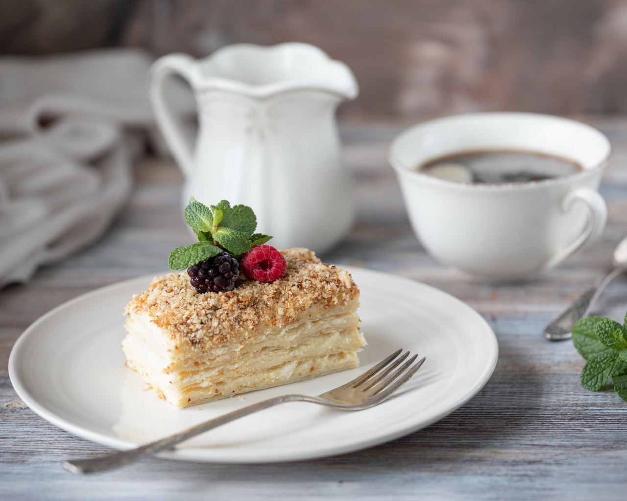 Кусок торта лежит на белой тарелке на столе с кофе