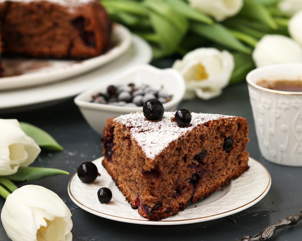 Кусок пирога со смородиной на столе с тюльпанами 