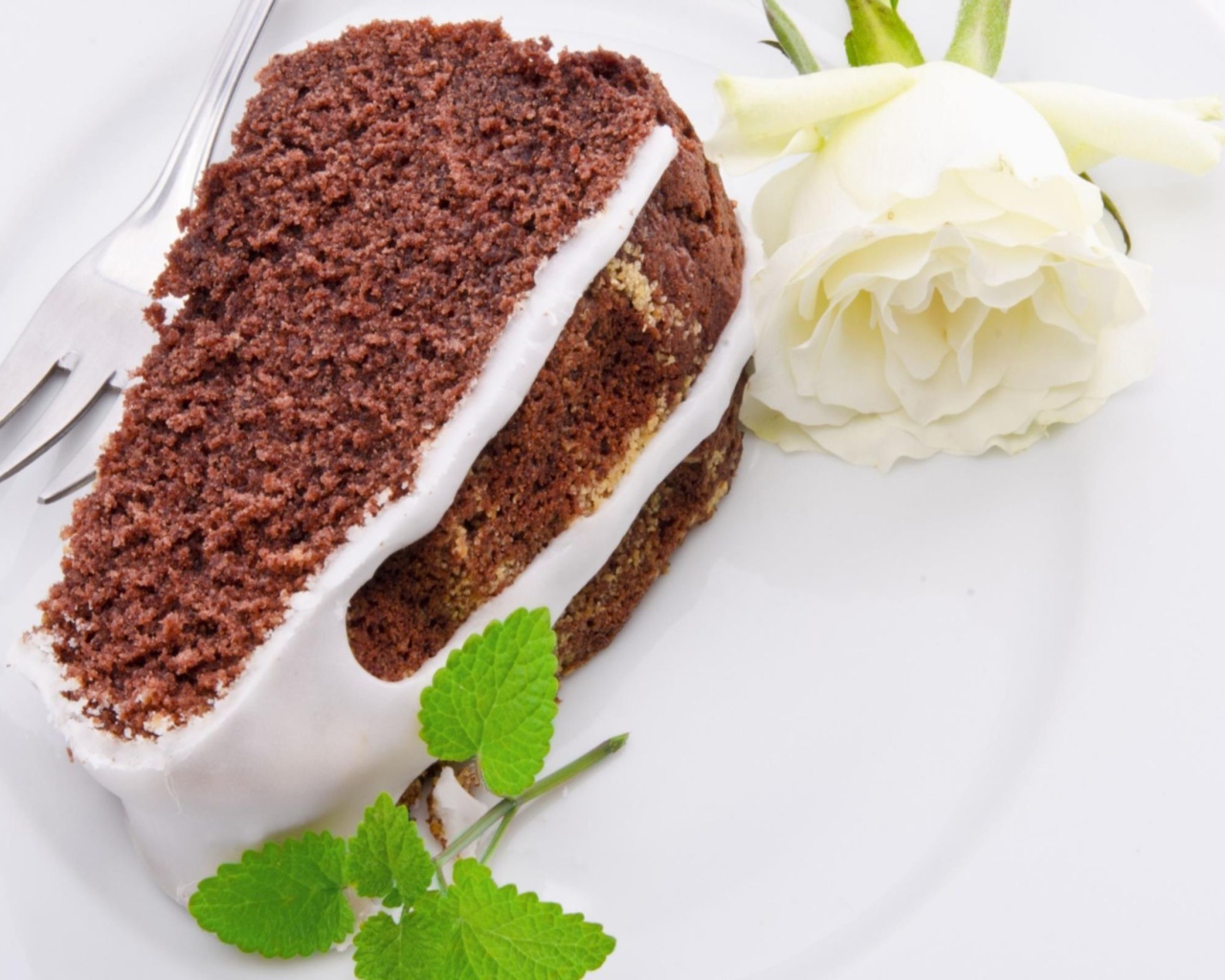 Кусок шоколадного пирога на тарелке с белой розой 