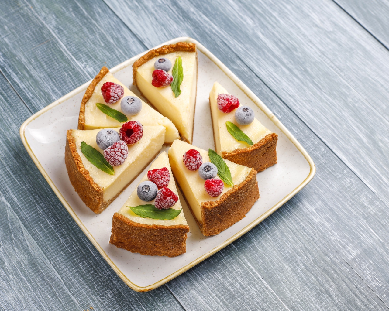 Аппетитный чизкейк с ягодами нарезан кусками на тарелке 