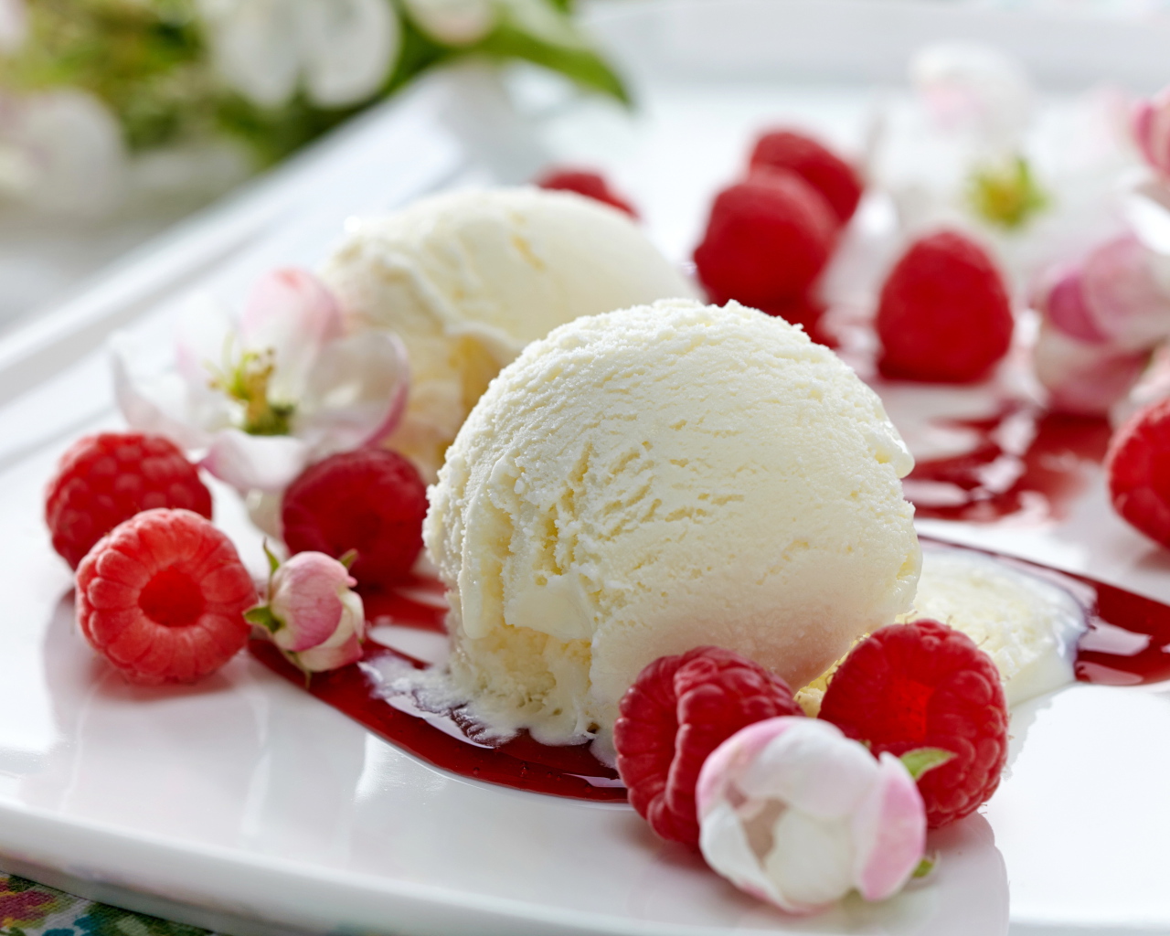 Шарики сливочного мороженого на тарелке с малиной и цветами