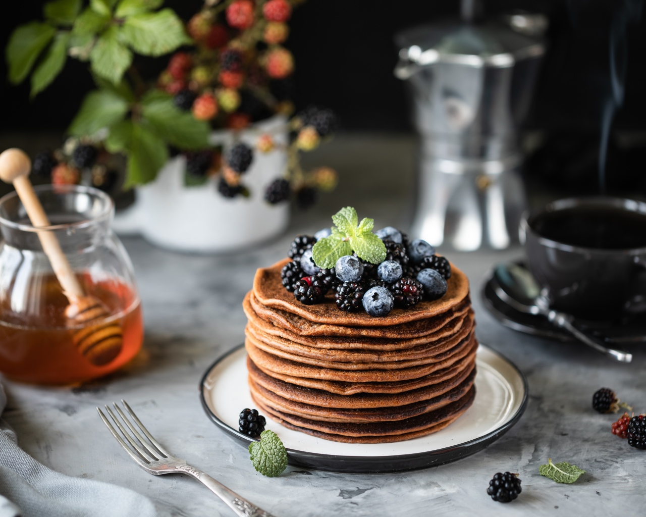 Гречневые блинчики с ягодами на столе с медом