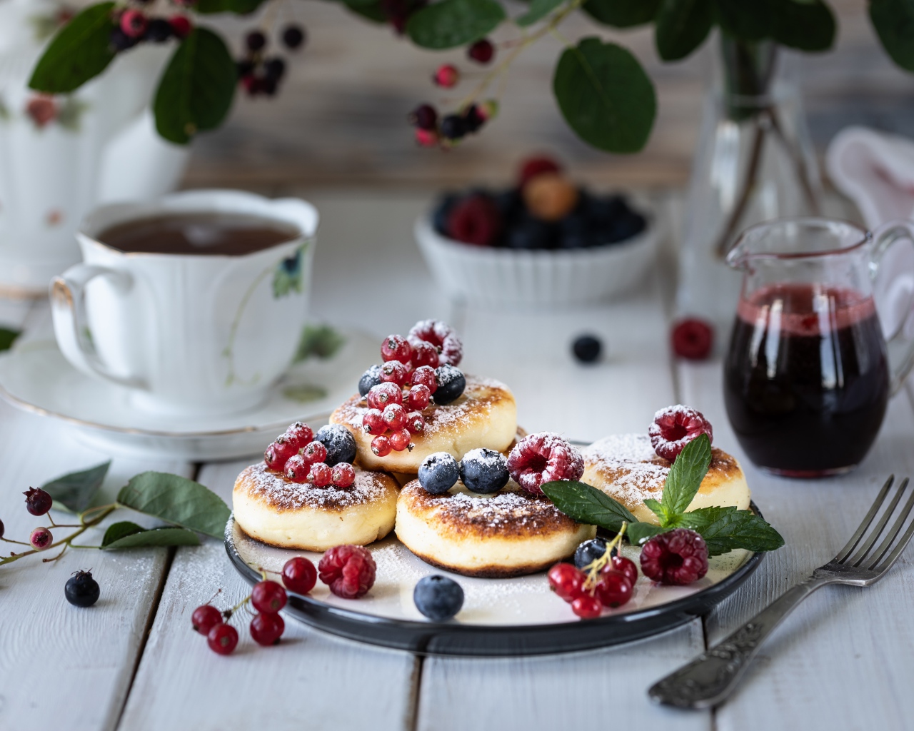 Сырники на столе с ягодами и чаем на завтрак