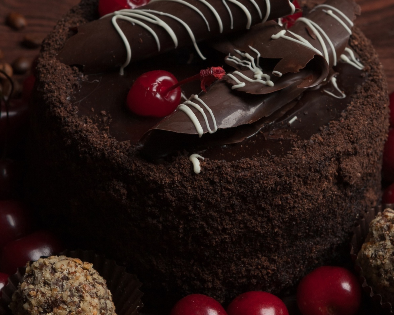 Шоколадный торт с конфетами и вишней на столе 