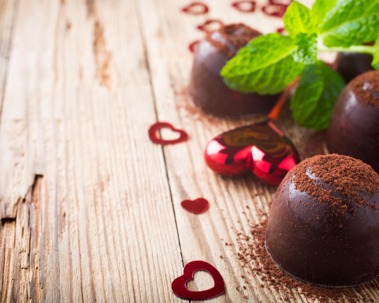 Шоколадные конфеты с какао на столе с мятой и сердечками