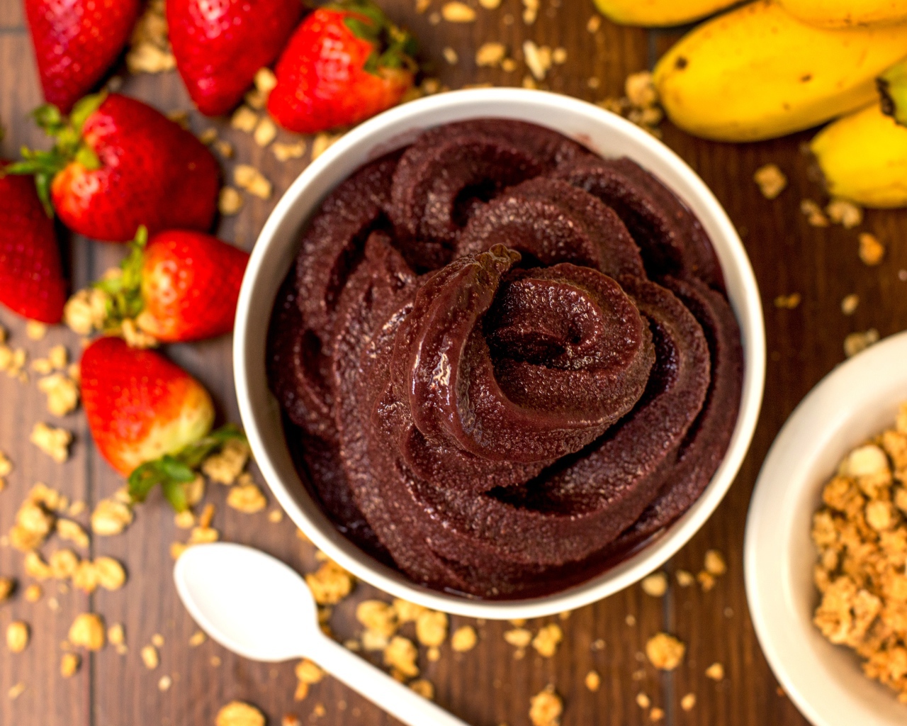 Шоколадная паста на столе с ягодами клубники и бананами