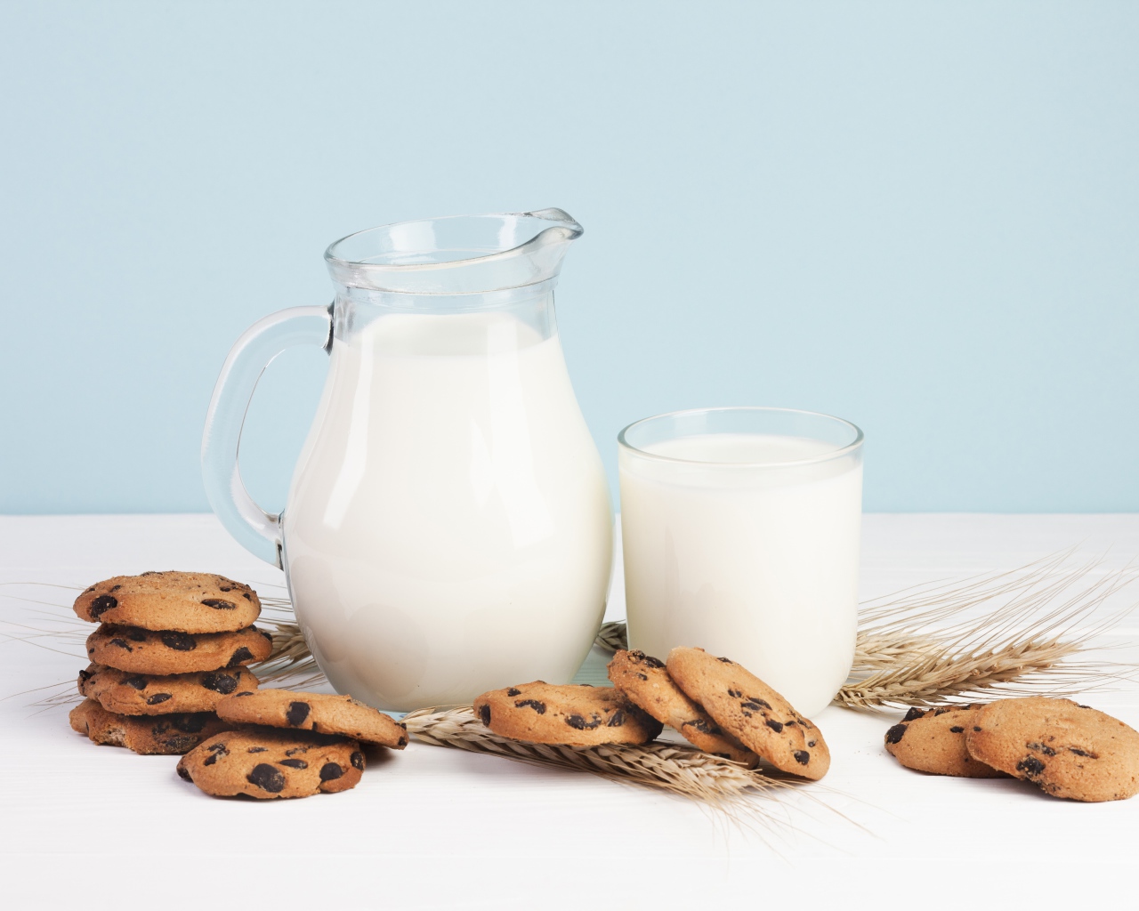 Печенье с шоколадом на столе с молоком и колосьями пшеницы