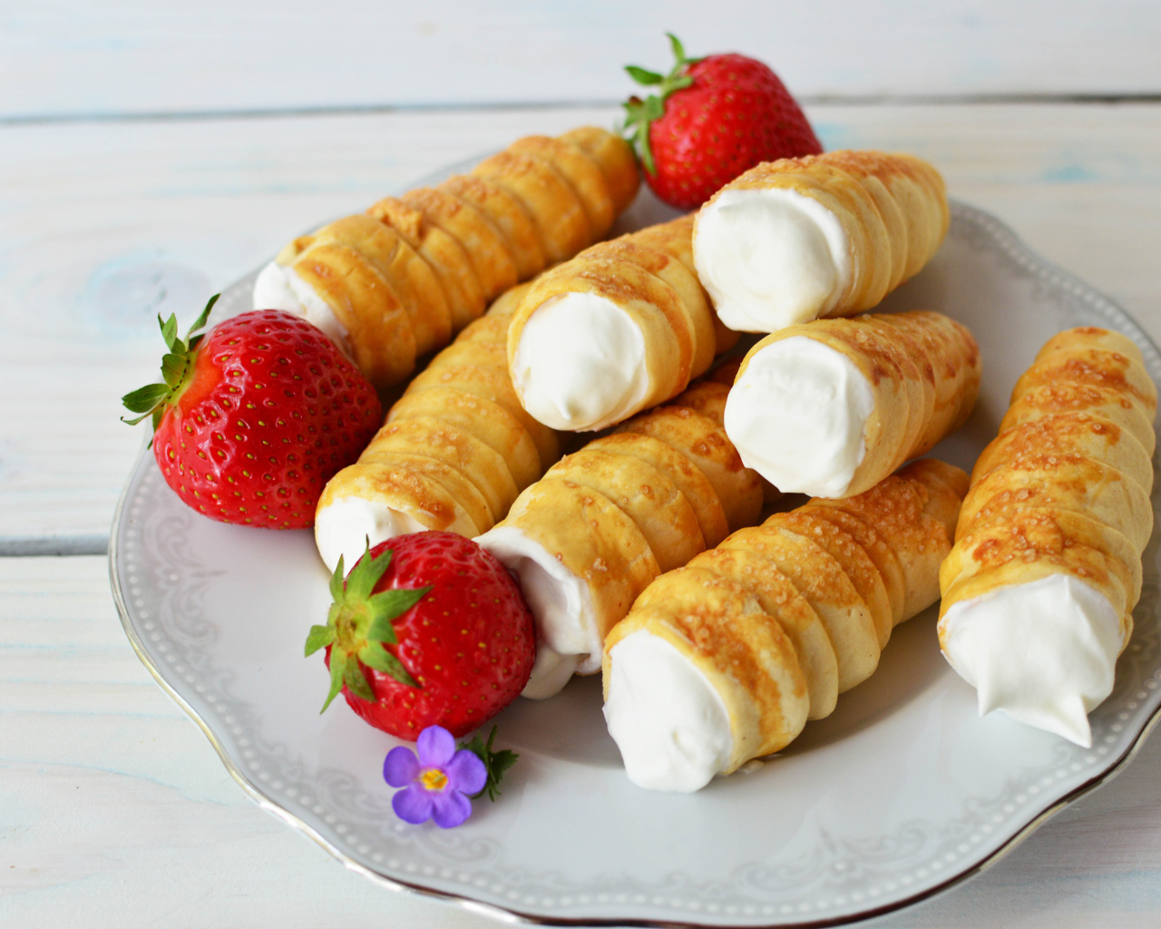 Пирожные с кремом на тарелке с клубникой