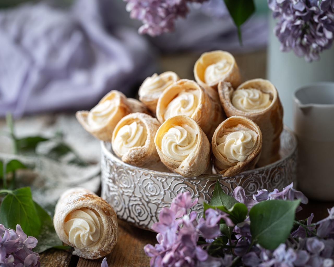 Трубочки с кремом на столе с цветами сирени