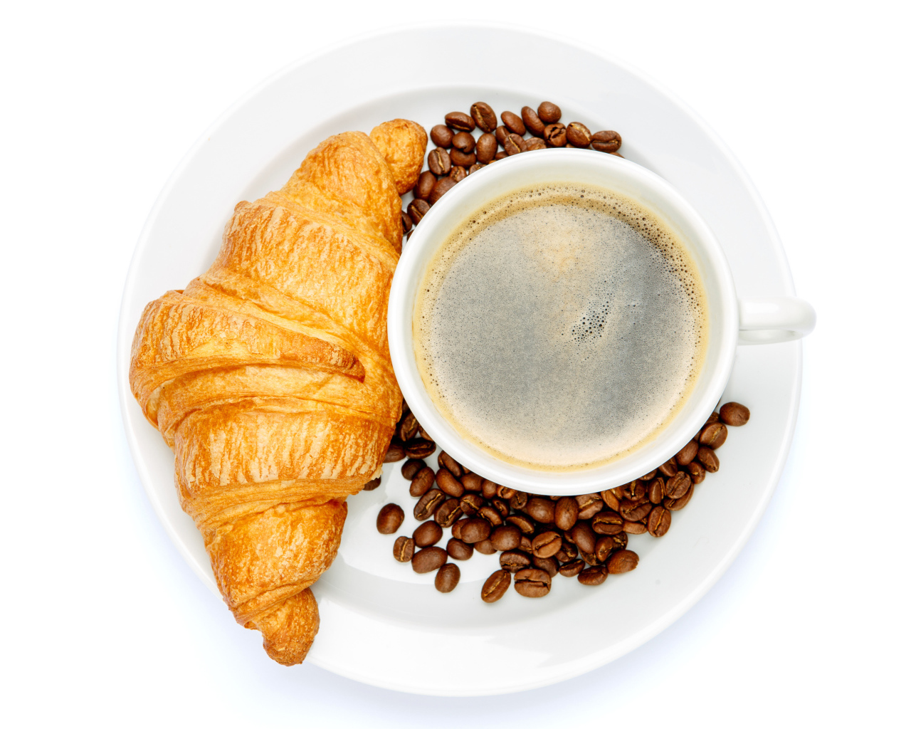 Чашка кофе на белой тарелке с круассаном и зернами, вид сверху 