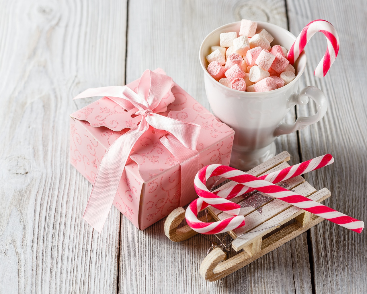 Чашка с маршмеллоу на столе с игрушечными санками и подарком