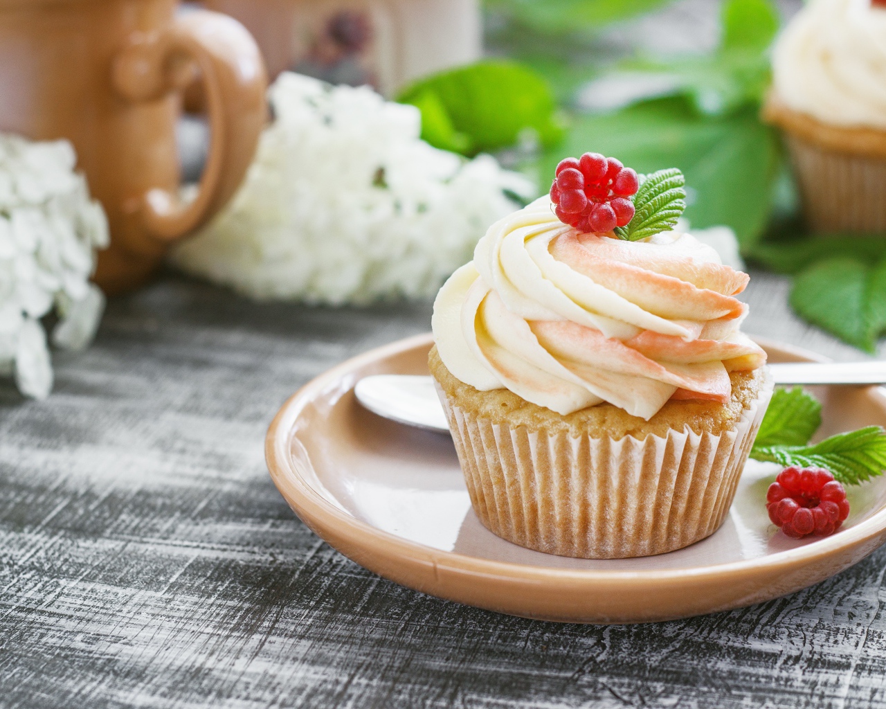 Кекс с кремом и малиной на столе