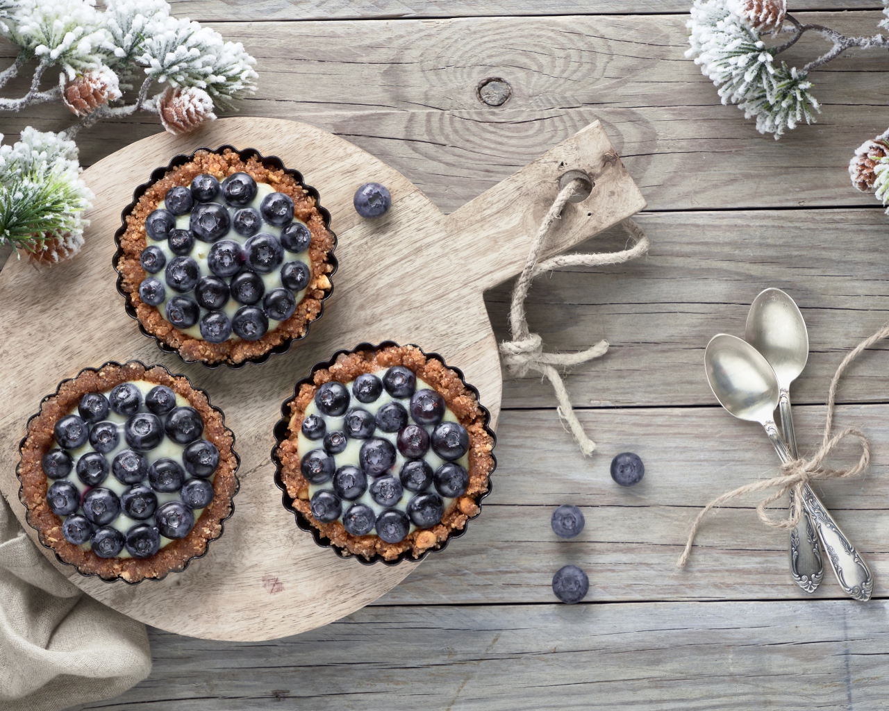 Кексы с кремом и ягодами черники на столе с чайными ложками