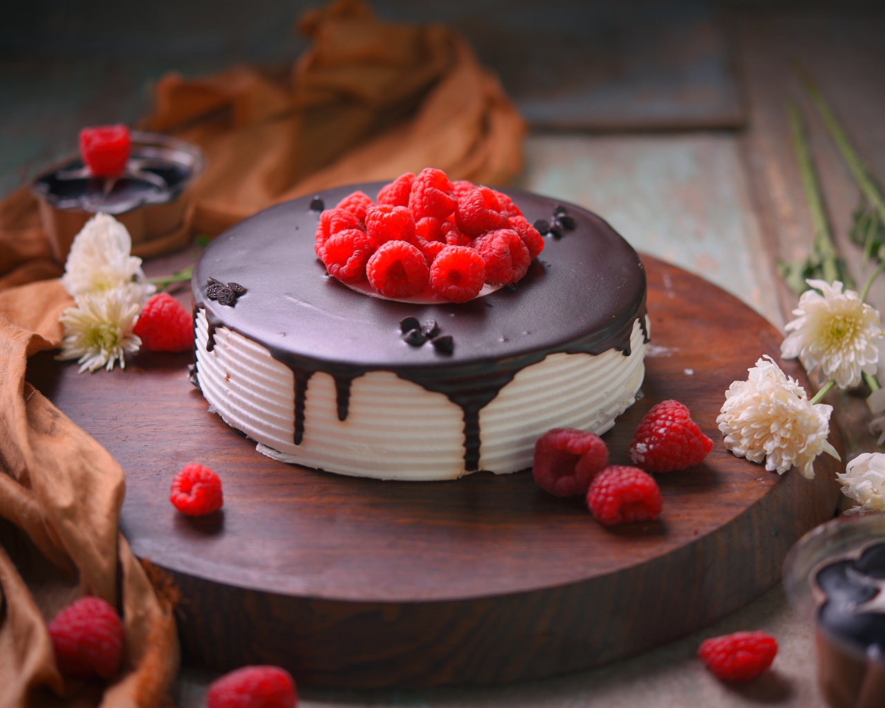 Вкусный торт с шоколадом и малиной на столе с цветами хризантемы 