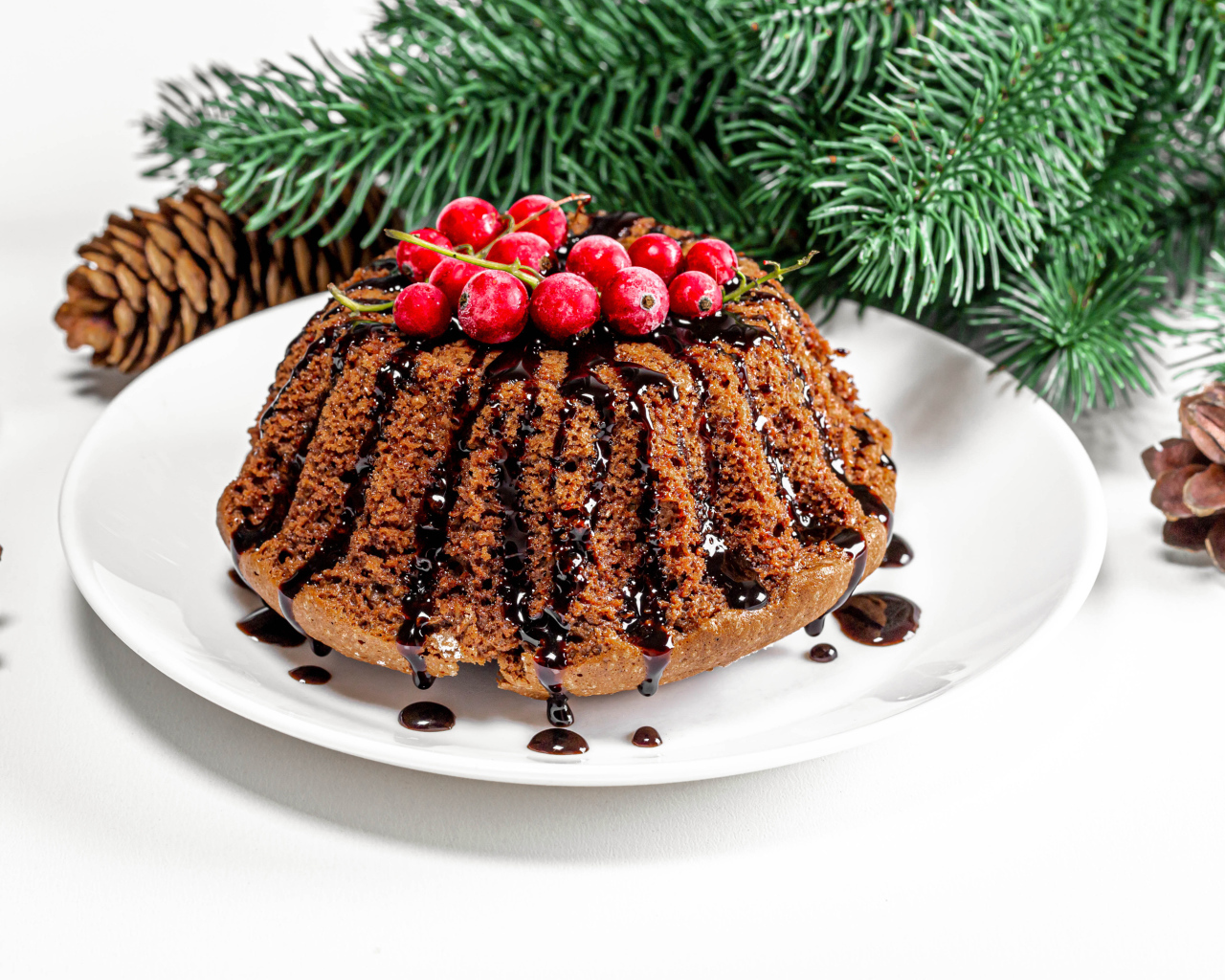 Вкусный кекс с шоколадом и красной смородиной на столе с еловой веткой и шишками