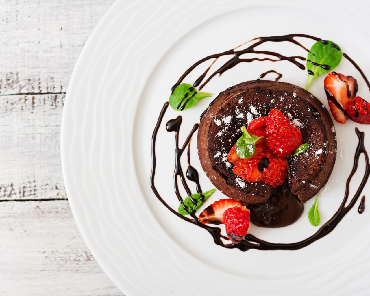 Вкусный десерт на белой тарелке с клубникой и шоколадом