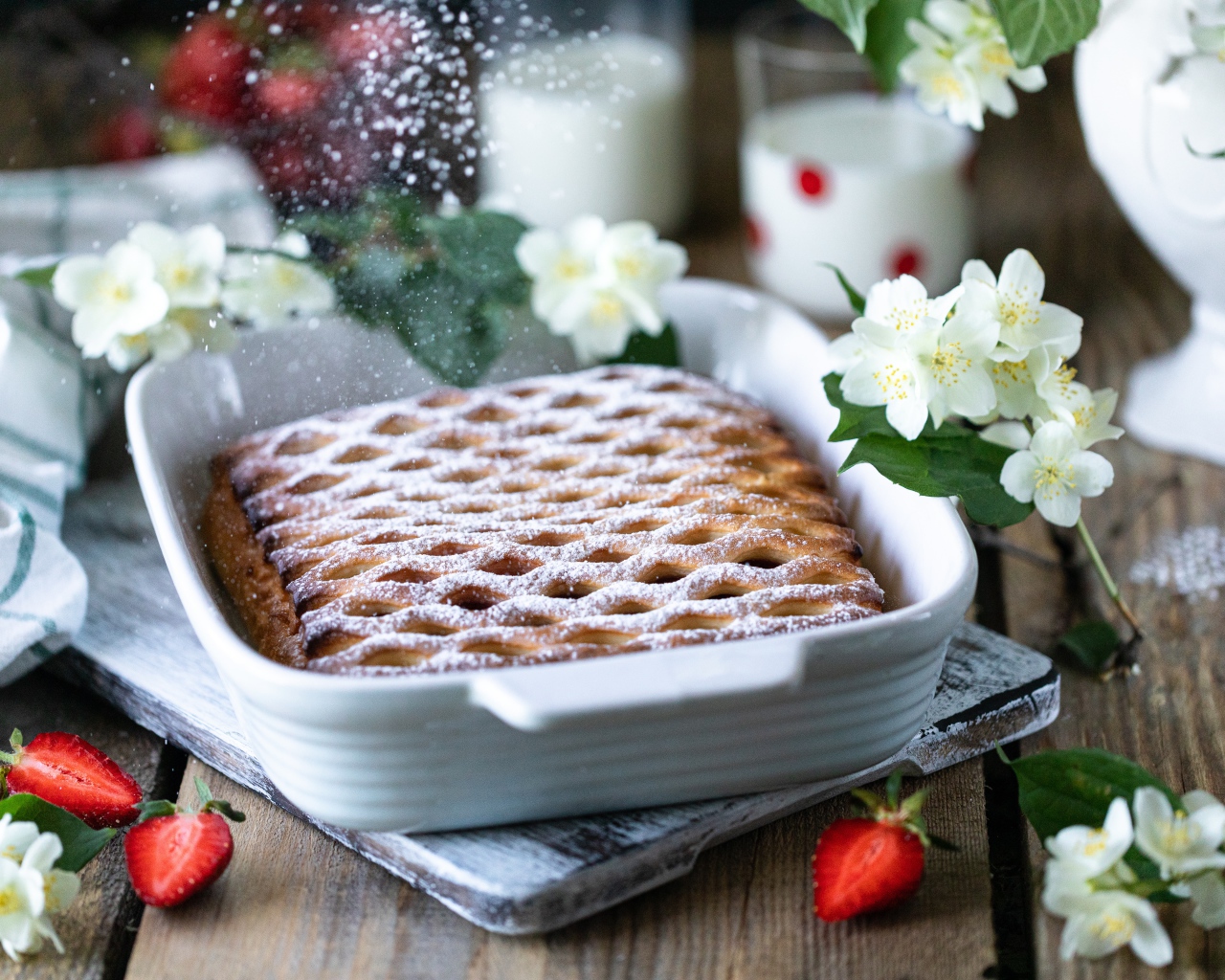Вкусный клубничный пирог с сахарной пудрой на столе с цветами жасмина