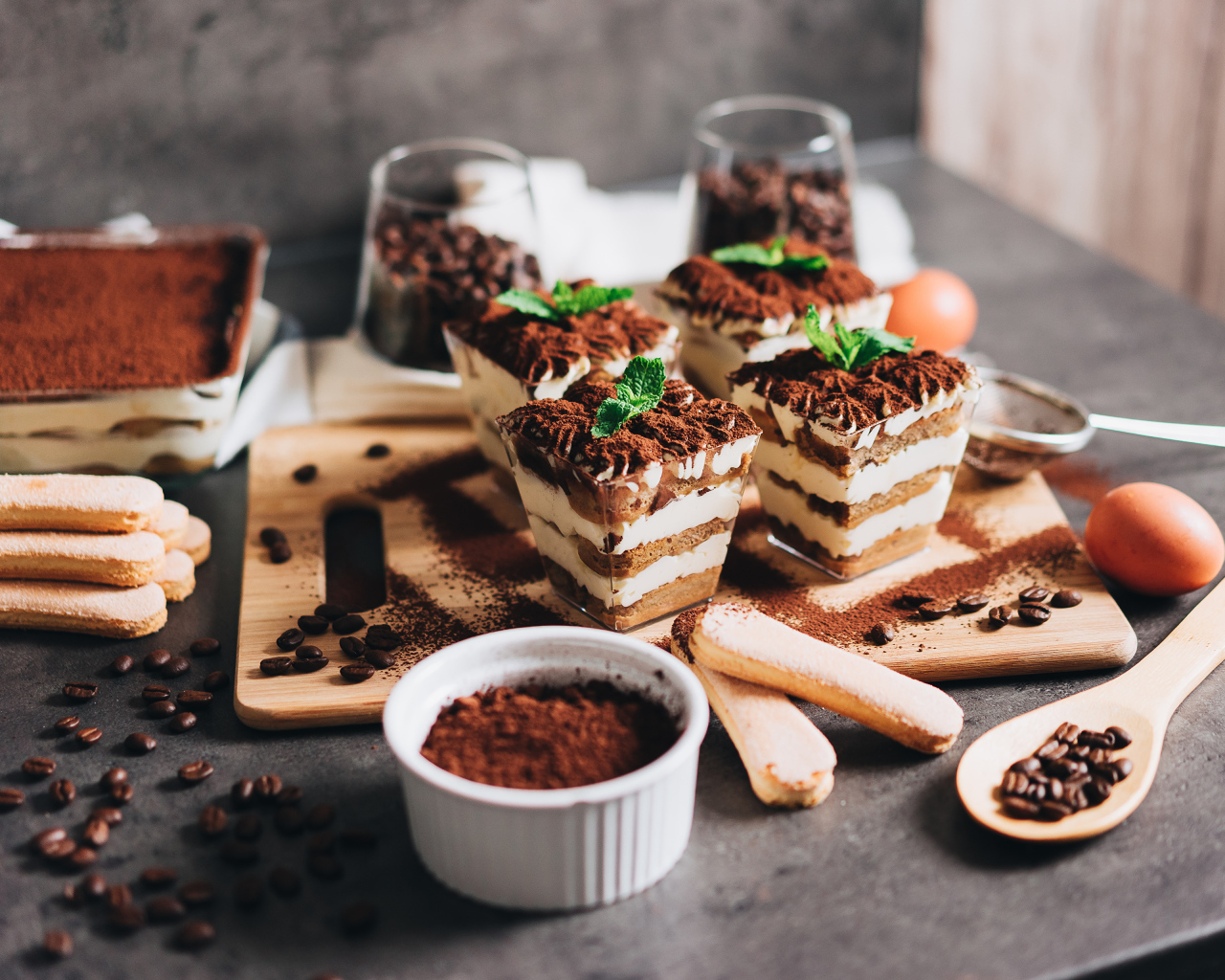 Аппетитный десерт тирамису в креманках на столе с кофейными зернами