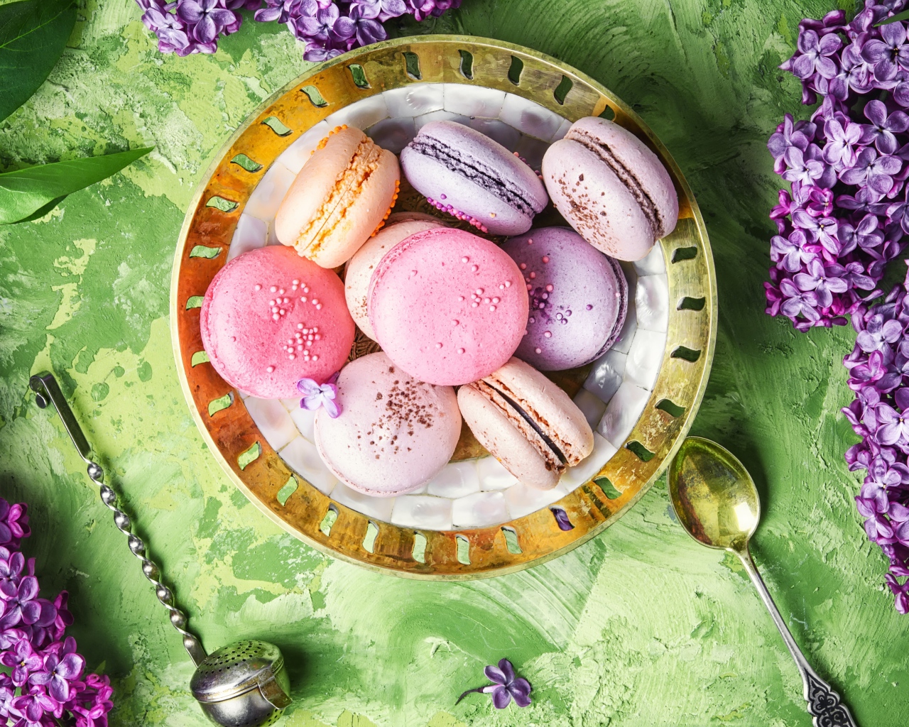 Разный десерт макарон на столе с цветами сирени 