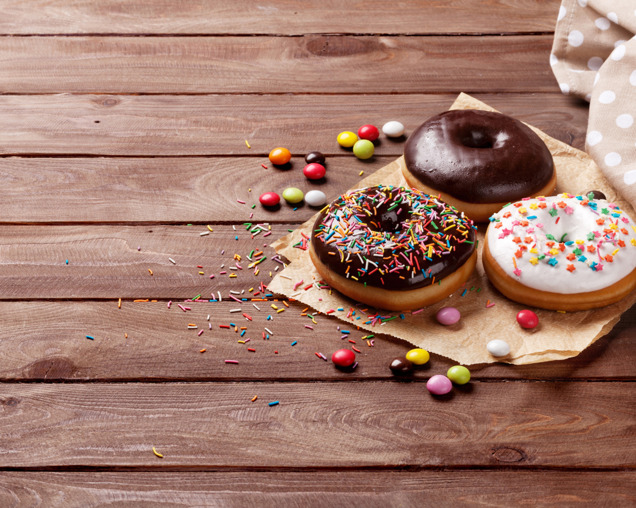 Пончики с глазурью на столе с конфетами на деревянном столе