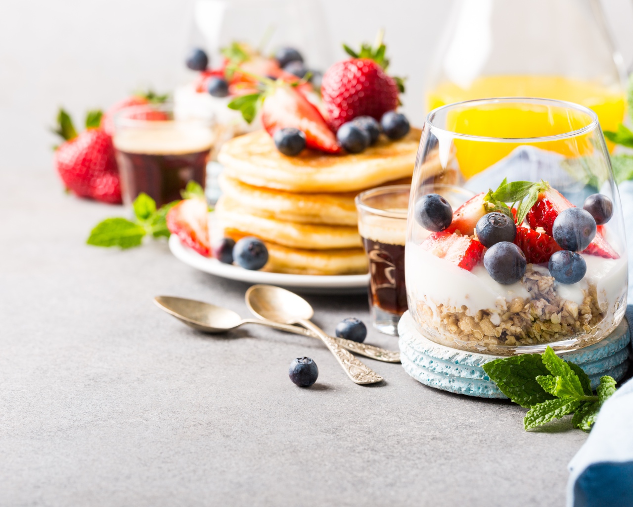 Оладьи на столе с ягодами, мюсли и кофе