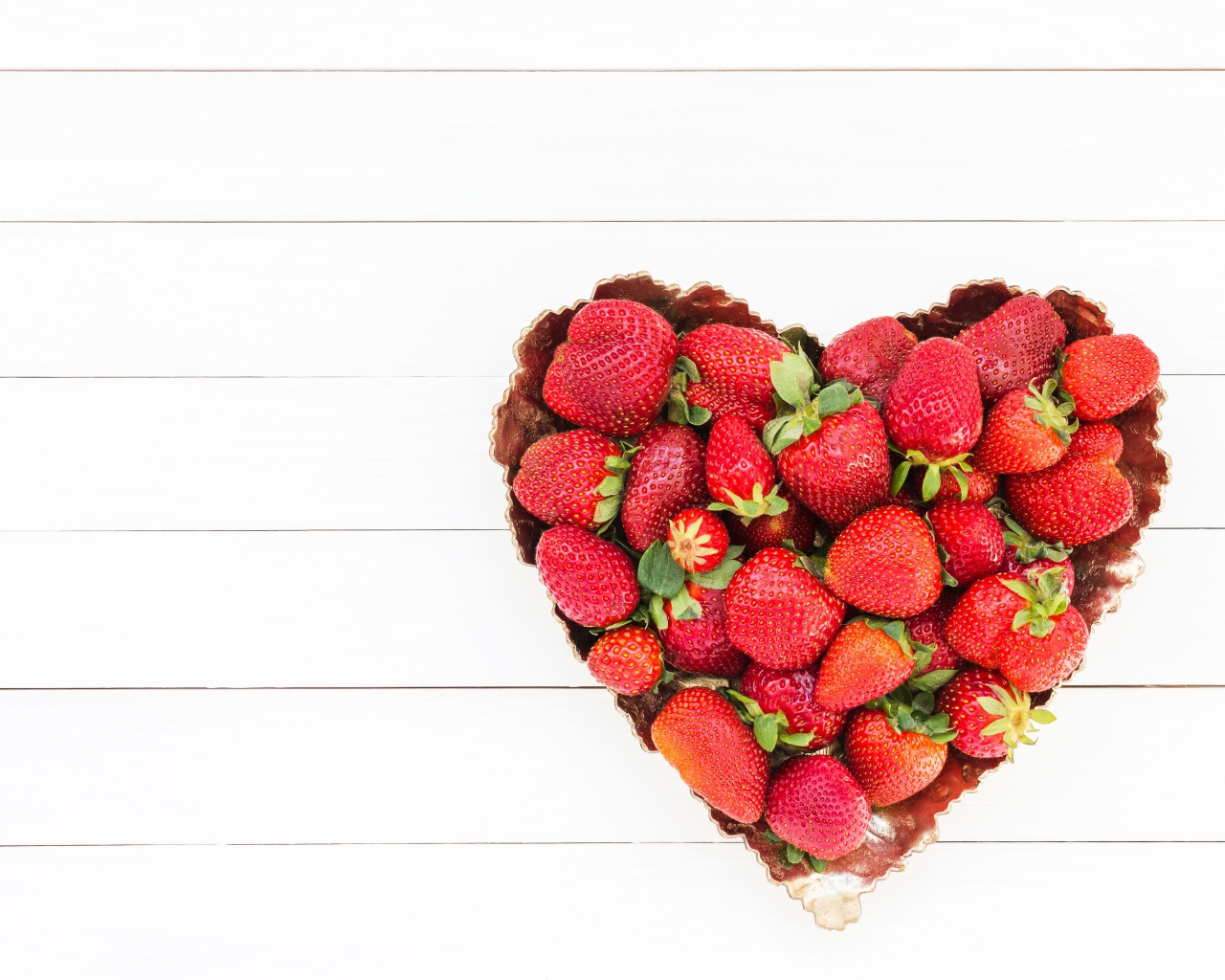 Пирожное в форме сердца с клубникой на белом фоне