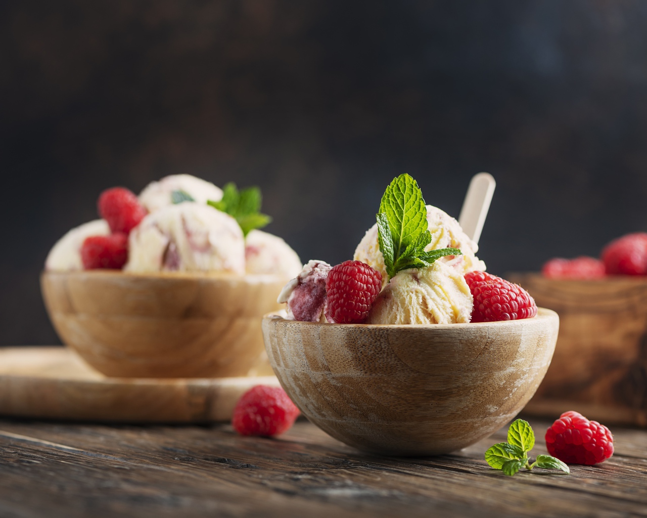 Шарики мороженого в деревянных мисках с ягодами малины