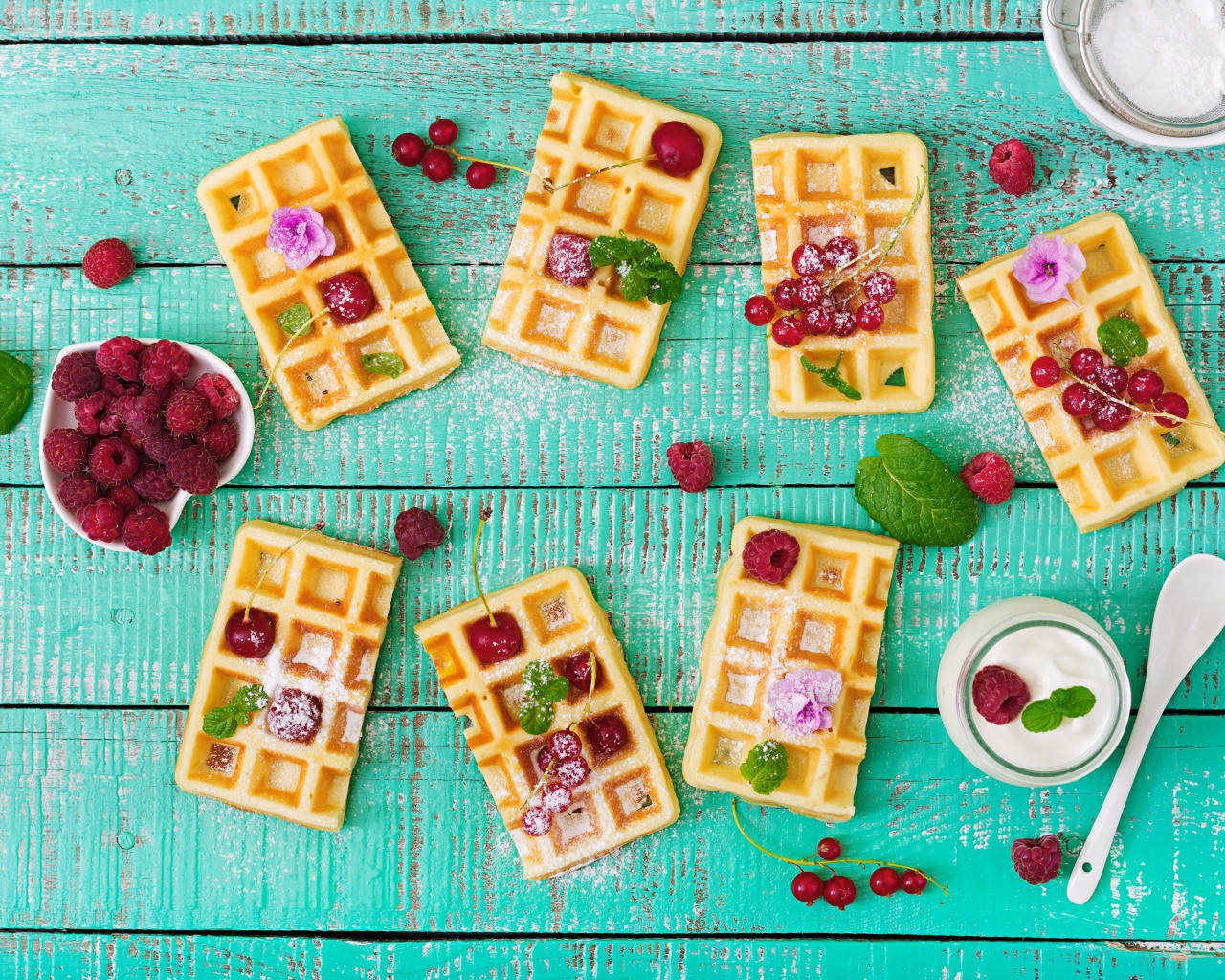 Большие сладкие вафли с ягодами и сахарной пудрой на столе 