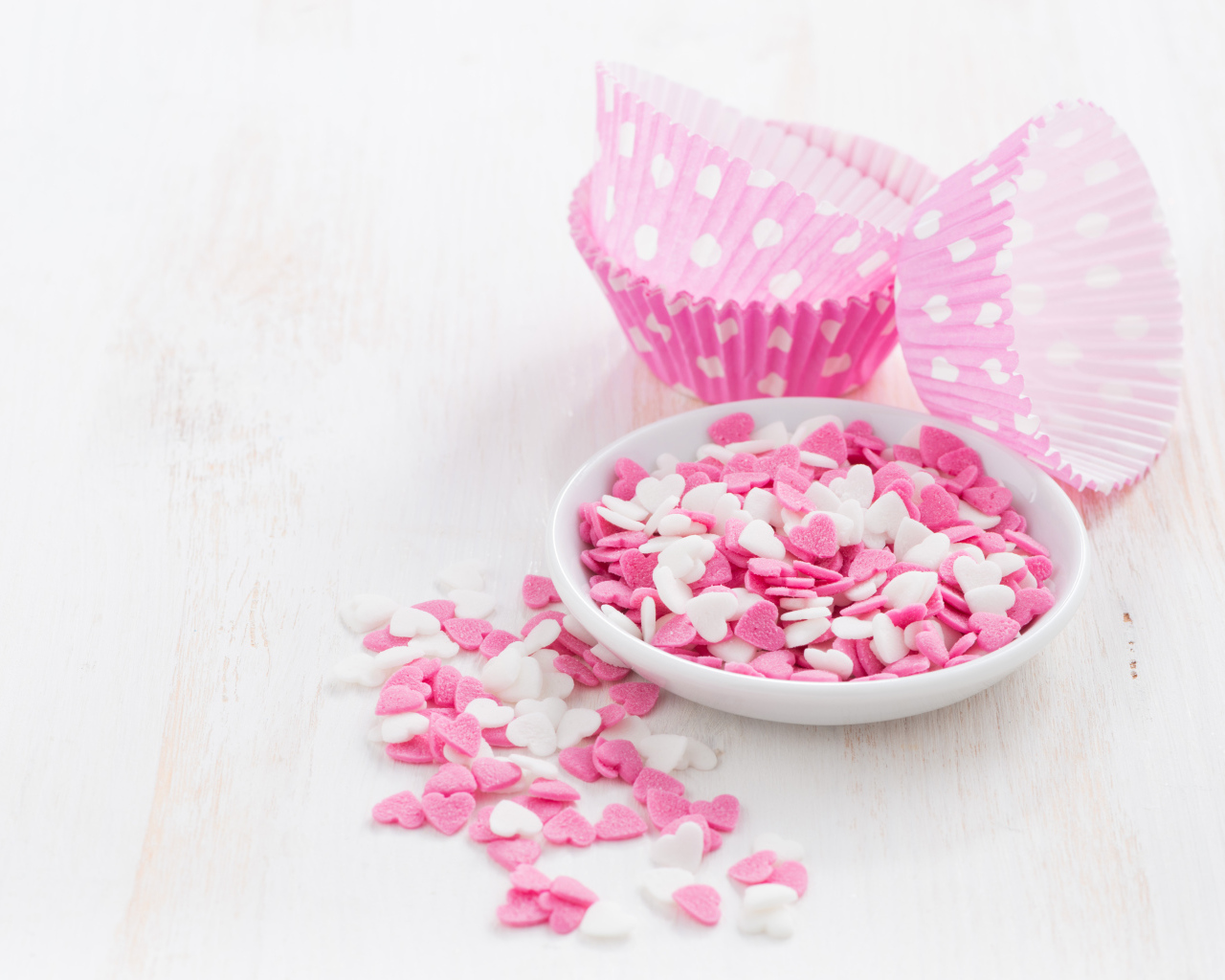 Маленькие белые и розовые сердечки на столе 