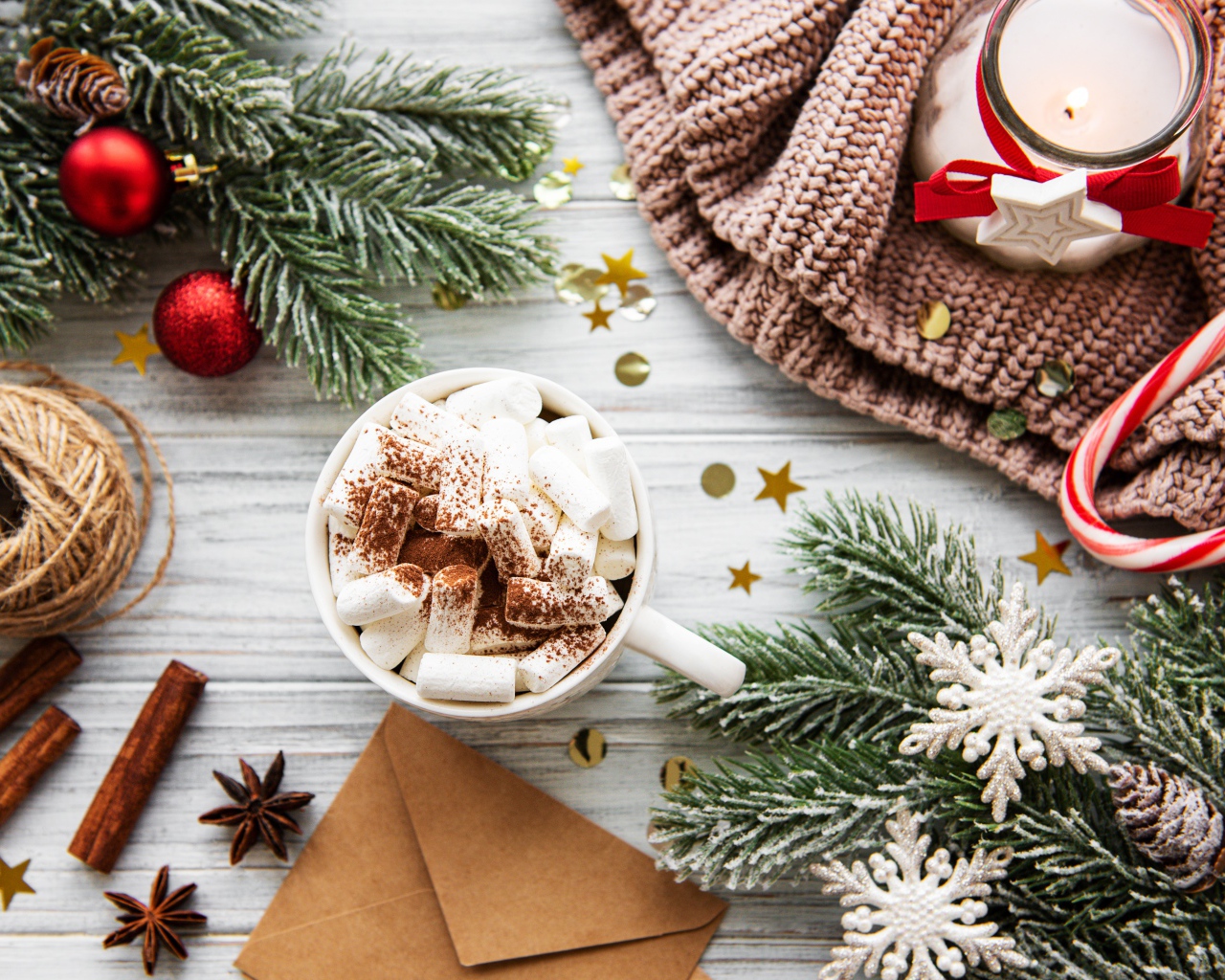 Кружка с маршмеллоу на столе с еловыми ветками и свечой