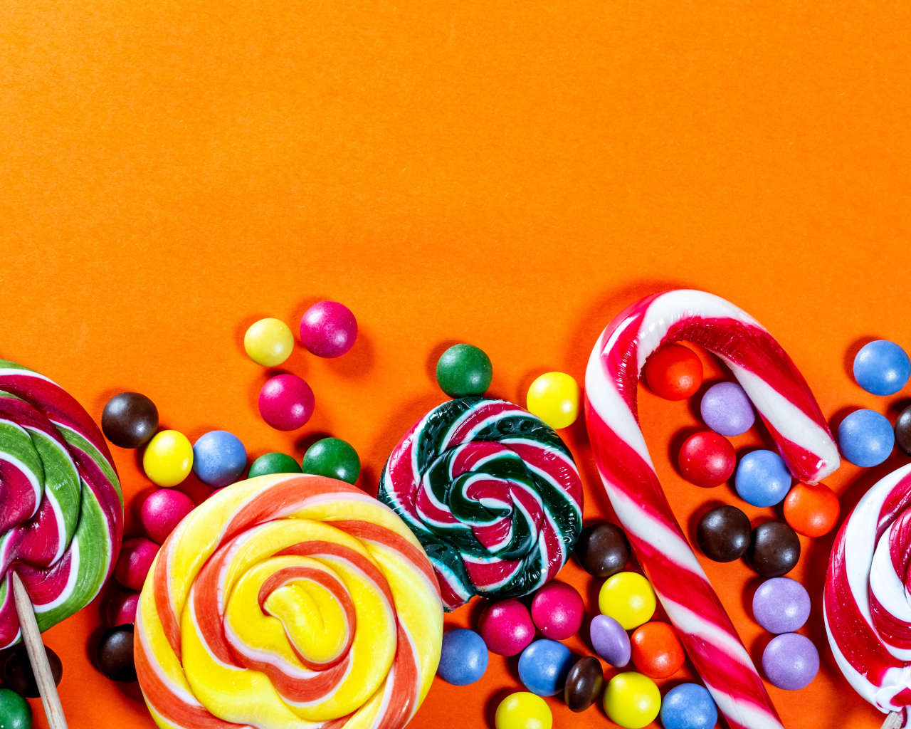 Разноцветные конфеты на оранжевом фоне