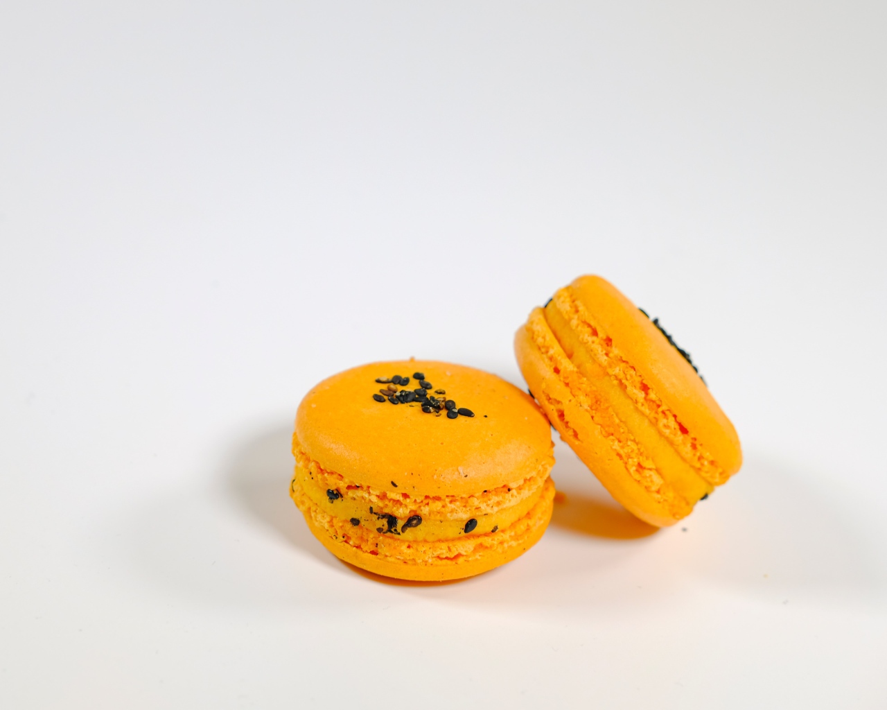 Оранжевый десерт макарон на сером фоне