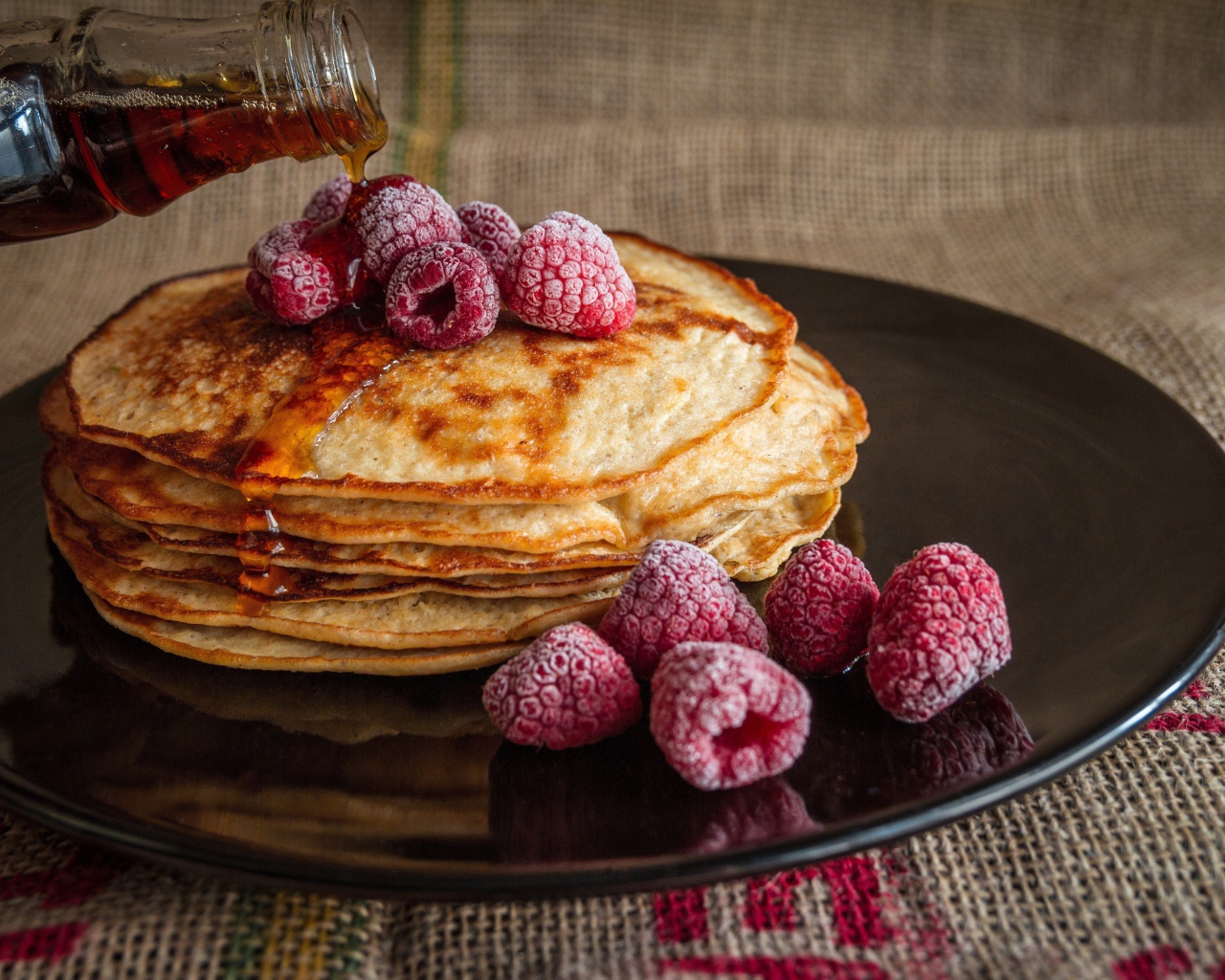 Блины с сиропом на тарелке с малиной