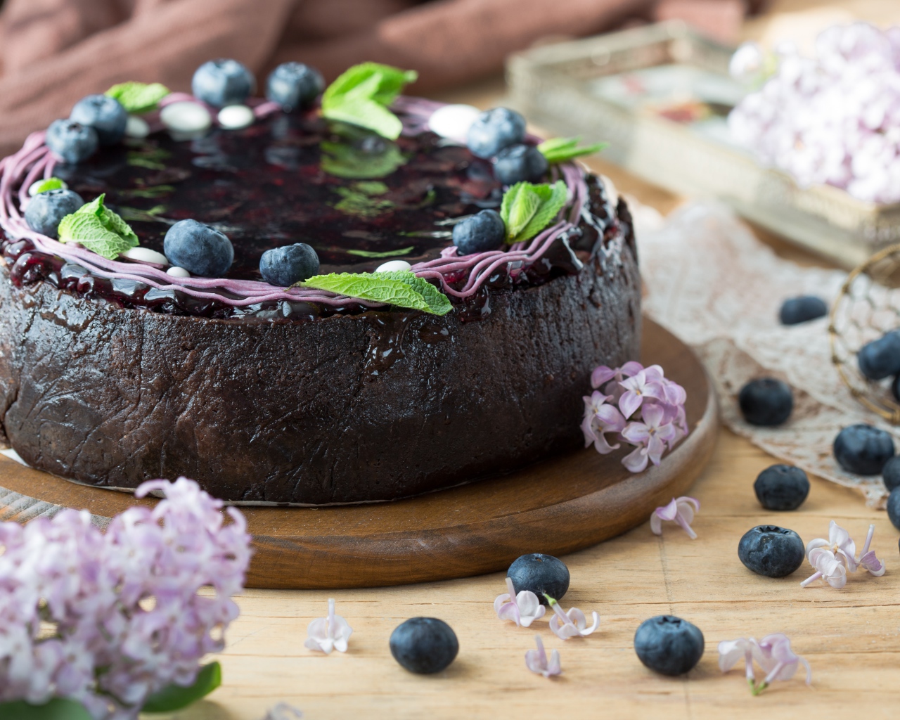 Пирог с джемом и ягодами черники на столе с сиренью 