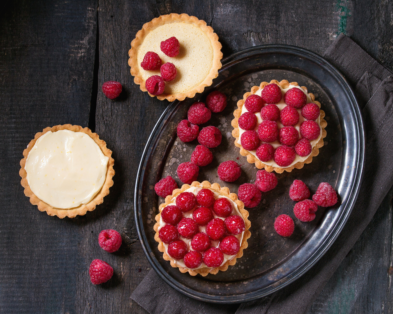 Кексы с кремом на блюде с малиной 