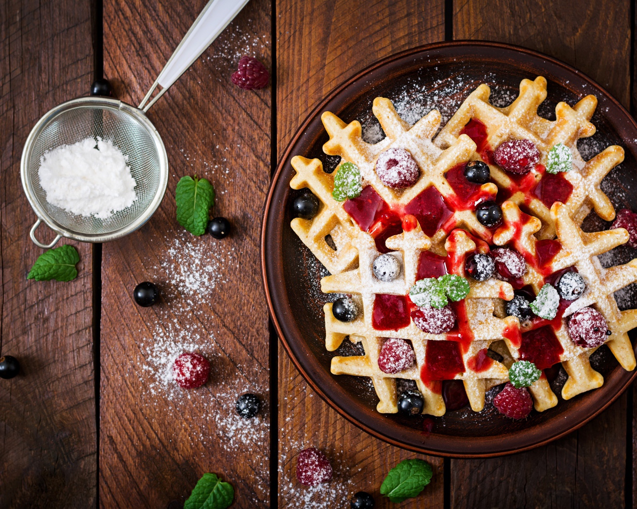 Сладкие медовые вафли на тарелке с ягодами и джемом и сахарной пудрой 