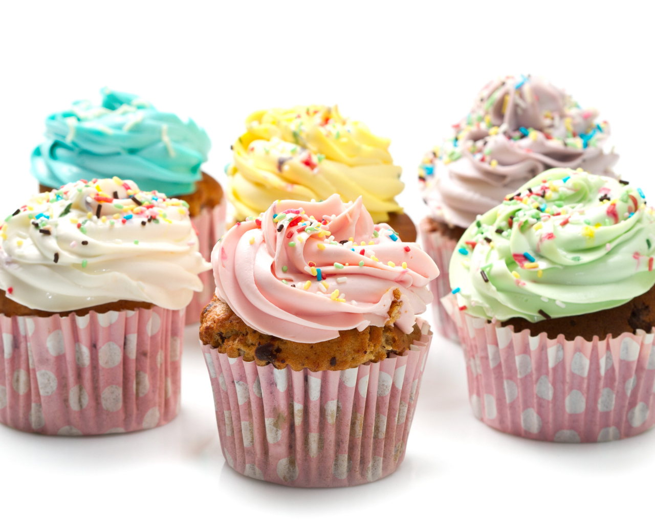 Сладкие кексы с кремом и посыпкой на белом фоне