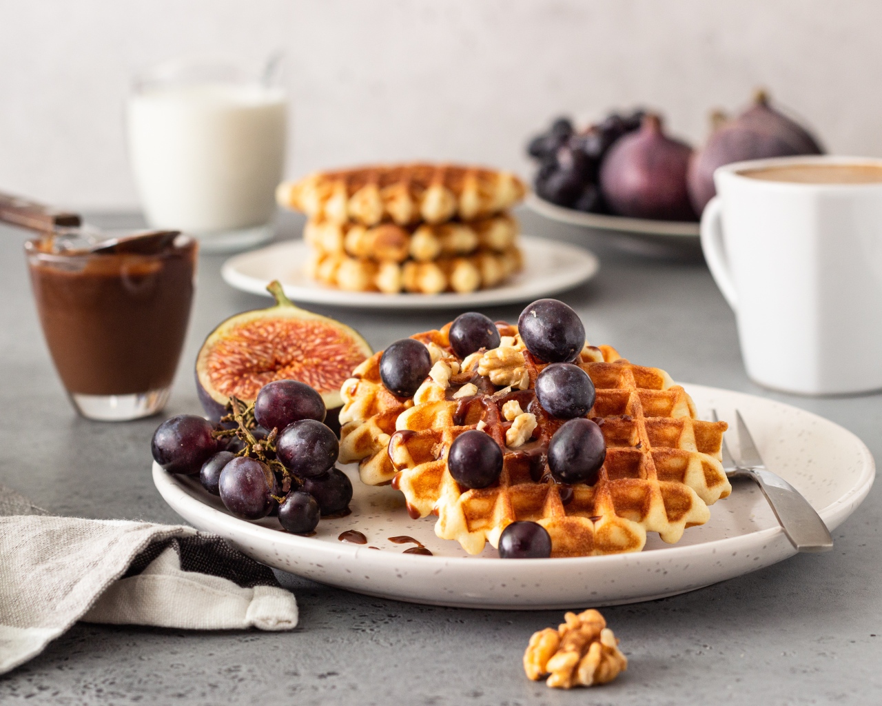 Сладкие вафли на тарелке с инжиром и виноградом