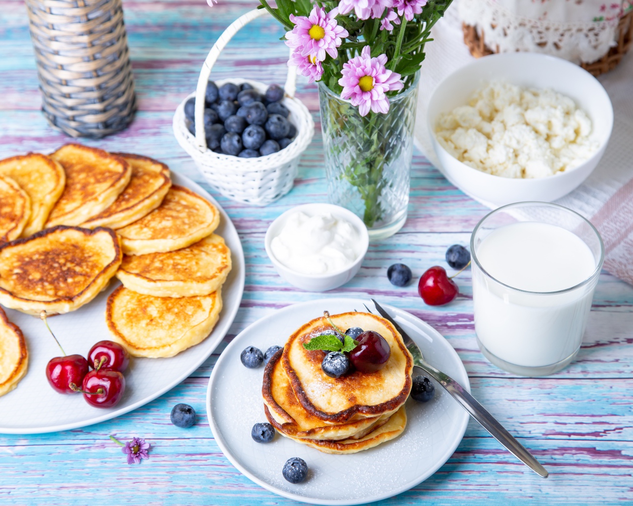 Вкусные оладьи на столе с ягодами черники, творогом и молоком