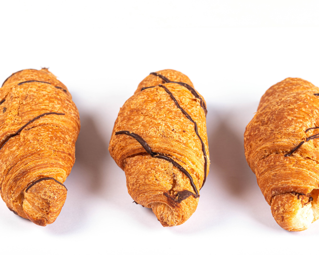 Три круассана с шоколадом на сером фоне